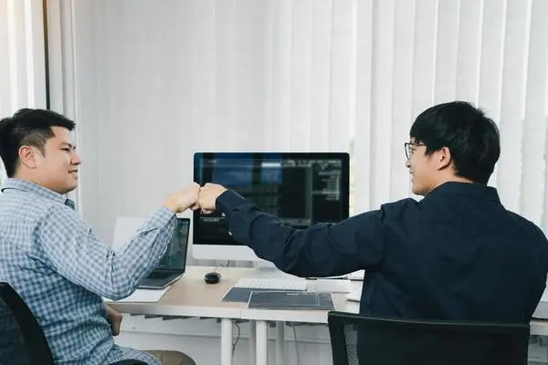 two asian people fist bump each other.